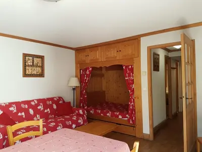 a living room with a red couch and a small room at Studio d'Anaite in Les Houches