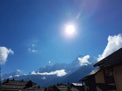 a sun in a blue sky with mountains in the background at Studio d'Anaite in Les Houches