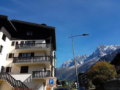 a white building with balconies and mountains in the background at Studio d'Anaite in Les Houches