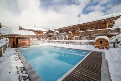 a house with a swimming pool in the snow at Les Loges Blanches Megève in Megève