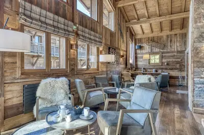 a room with chairs and tables and windows at Les Loges Blanches Megève in Megève