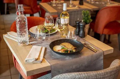 a table with a plate of food and glasses of wine at Les Loges Blanches Megève in Megève