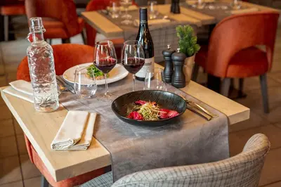 a table with a bowl of food and glasses of wine at Les Loges Blanches Megève in Megève