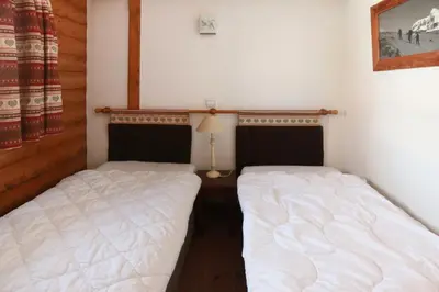 two twin beds in a bedroom with a lamp on a table at Residence La Ginabelle - maeva Home in Chamonix-Mont-Blanc