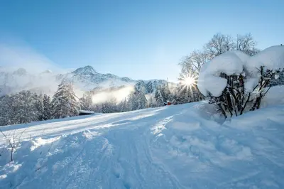 a road covered in snow with mountains in the background at APARTMENT REFUGE DE BELLACHAT - Alpes Travel - Les Houches - Sleeps 4 in Les Houches