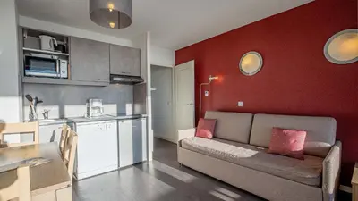 a living room with a couch and a kitchen at Madame Vacances Les Terrasses De Véret in Flaine