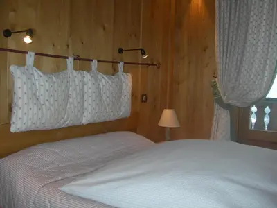 a bedroom with a bed with white sheets and a window at Le Cordonant in Cordon