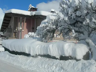 a fence covered in snow in front of a house at Le Cordonant in Cordon