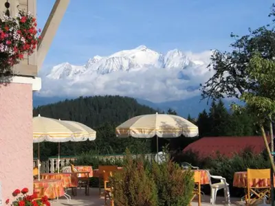 a restaurant with tables and umbrellas in front of a mountain at Le Cordonant in Cordon