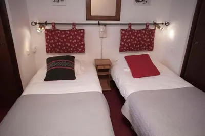 two beds in a small room with red pillows at Hôtel Val d'Este in Saint-Gervais-les-Bains