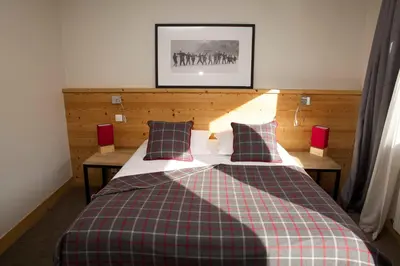 a bedroom with a bed with a checkered blanket at Hôtel Val d'Este in Saint-Gervais-les-Bains