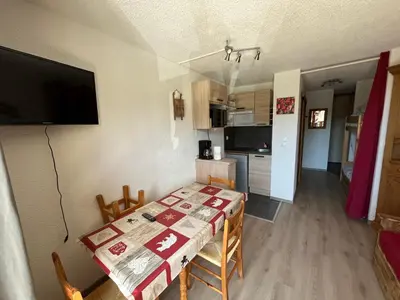 a kitchen and dining room with a table and a television at Grand Studio in Les Carroz d'Araches