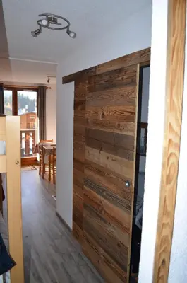 a wooden sliding door in a room with a dining room at Grand Studio in Les Carroz d'Araches