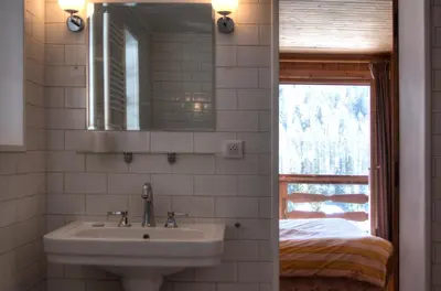a bathroom with a sink and a mirror and a bed at La Ribambelle in Chamonix-Mont-Blanc