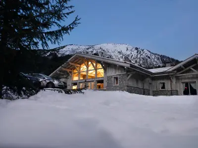 a house in the snow with a car parked in front at CGH Résidence Boutique Le Hameau De Pierre Blanche in Les Houches