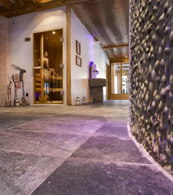 a room with a stone wall and a man in a store at CGH Résidence Boutique Le Hameau De Pierre Blanche in Les Houches