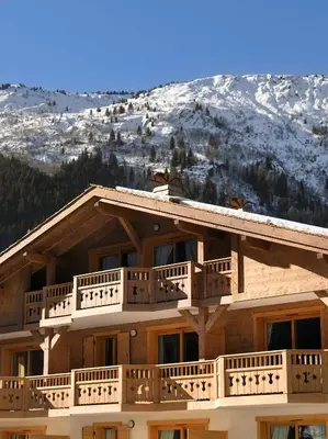 a ski lodge with a snow covered mountain in the background at CGH Résidence Boutique Le Hameau De Pierre Blanche in Les Houches