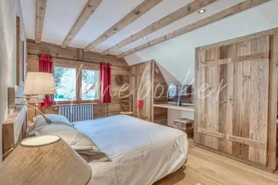 a bedroom with a bed and a wooden wall at Chalet Hermine in Megève