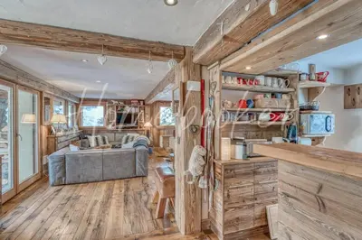 a kitchen and living room with wooden walls and wooden floors at Chalet Hermine in Megève