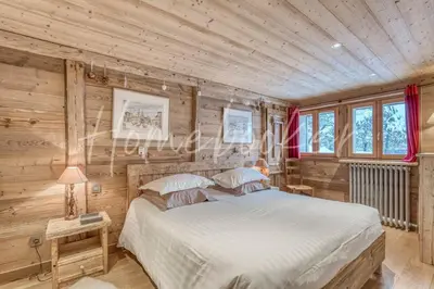 a bedroom with a bed and wooden walls and windows at Chalet Hermine in Megève