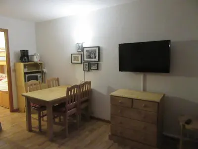 a dining room with a table and a television on a wall at Le Prarion 2 in Les Houches