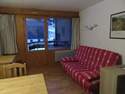 a living room with a red couch and a table at Le Prarion 2 in Les Houches