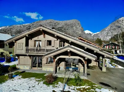 a large wooden house with mountains in the background at Chalet Luxe Les Mélèzes in Samoëns