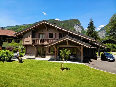 a large wooden house with a green lawn in front of it at Chalet Luxe Les Mélèzes in Samoëns