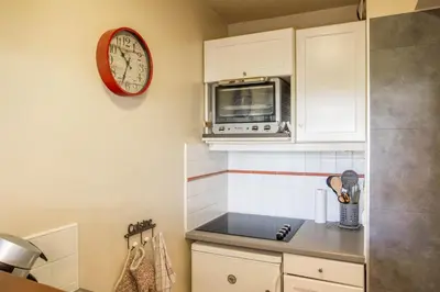 a kitchen with a microwave and a clock on the wall at Au Pied Du Mont-Blanc - Chamonix in Chamonix-Mont-Blanc