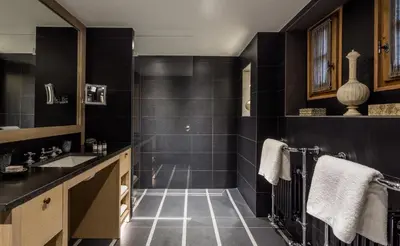 a bathroom with black tiles and a sink at Les Chalets du Mont d'Arbois & Spa, Megève in Megève