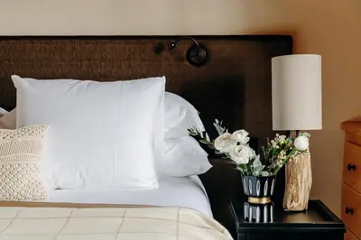 a bed with white pillows and flowers on a night stand at Les Chalets du Mont d'Arbois & Spa, Megève in Megève