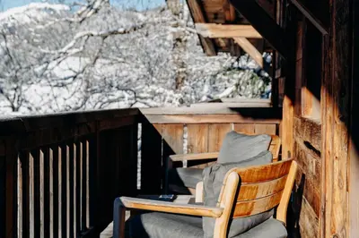 a porch with a chair and a snow covered mountain at Les Chalets du Mont d'Arbois & Spa, Megève in Megève