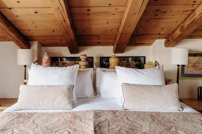 a bedroom with a bed with white pillows and wooden ceilings at Les Chalets du Mont d'Arbois & Spa, Megève in Megève
