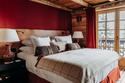a bedroom with a large bed with red walls at Les Chalets du Mont d'Arbois & Spa, Megève in Megève