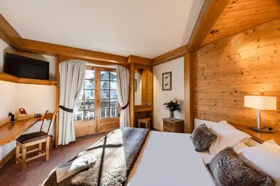 a bedroom with a bed and a desk and a window at Hôtel La Grange d'Arly in Megève