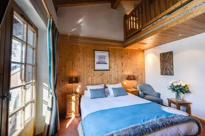 a bedroom with a large bed and a wooden wall at Hôtel La Grange d'Arly in Megève