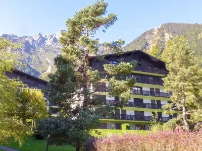 a hotel with trees and mountains in the background at Apartment Le Brévent-22 by Interhome in Chamonix-Mont-Blanc