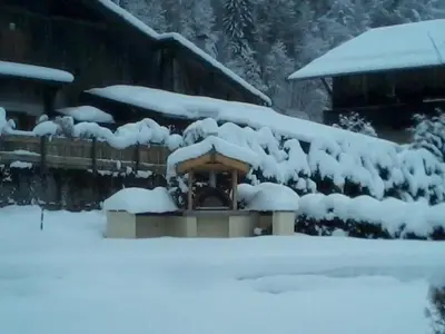 a gazebo covered in snow next to a house at Ferme Dowena in Morillon