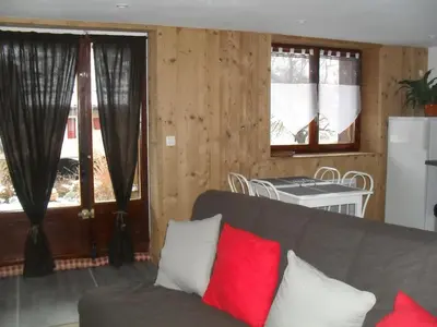 a living room with a couch and a table and windows at Les Clarines in Saint-Gervais-les-Bains