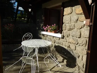 a table and chairs next to a stone wall at Les Clarines in Saint-Gervais-les-Bains