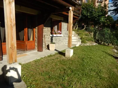 a stone house with a porch and a grass yard at Les Clarines in Saint-Gervais-les-Bains