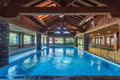 a swimming pool in a house with a wooden ceiling at Résidence Pierre & Vacances Premium Les Fermes Du Soleil in Les Carroz d'Araches