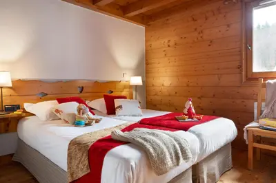 a bedroom with two dolls sitting on a bed at Résidence Pierre & Vacances Premium Les Fermes Du Soleil in Les Carroz d'Araches