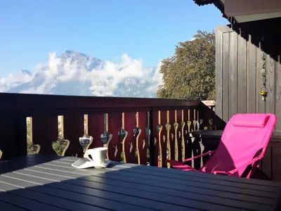 a table with wine glasses and a chair on a balcony at BelleVue centre, wifi, mountain view in Les Carroz d'Araches