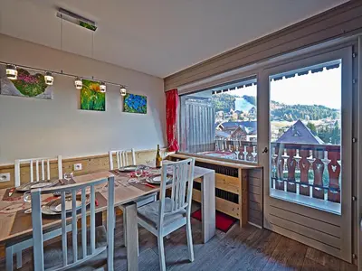 a dining room with a table and chairs and a window at BelleVue centre, wifi, mountain view in Les Carroz d'Araches