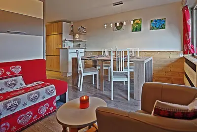 a living room and kitchen with a table and chairs at BelleVue centre, wifi, mountain view in Les Carroz d'Araches