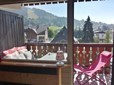 a balcony with a pink chair and a large window at BelleVue centre, wifi, mountain view in Les Carroz d'Araches