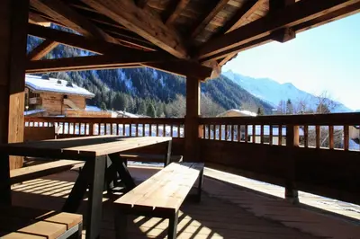 a wooden deck with a wooden picnic table and bench at Chalets Grands Montets in Chamonix-Mont-Blanc