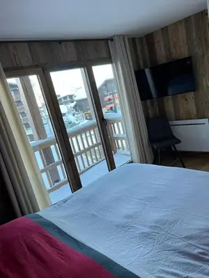 a bedroom with a bed and a view of a balcony at Les Carroz d'Araches in Les Carroz d'Araches