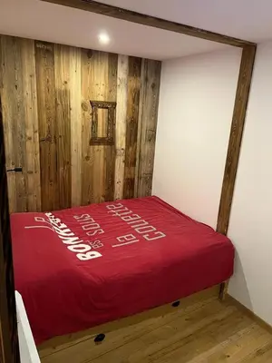 a bed in a room with a red blanket at Les Carroz d'Araches in Les Carroz d'Araches